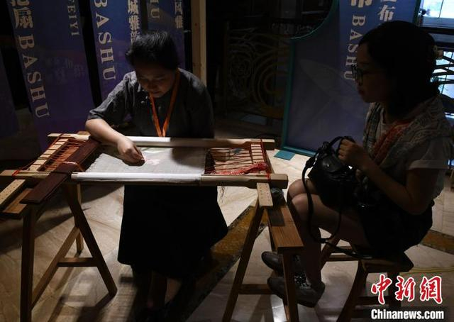 图为展览现场，工作人员展示刺绣技艺吸引市民欣赏。中新社记者 周毅 摄 