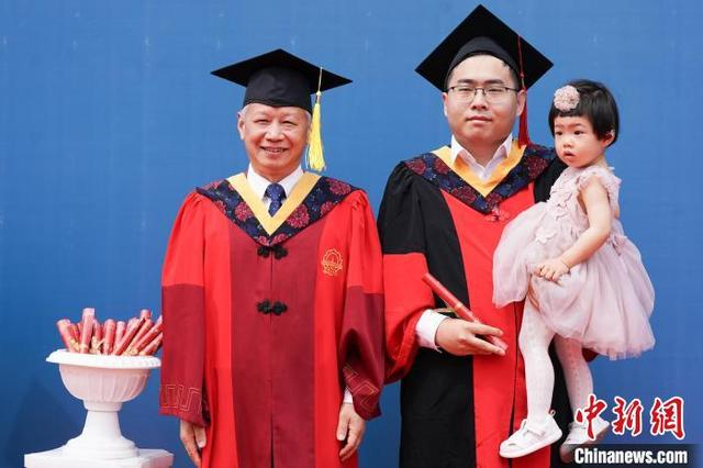图为一名毕业生带着孩子参加毕业典礼。中新社记者 赵宇航 摄 