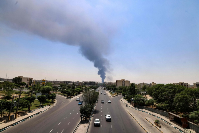 这是6月15日在伊朗首都德黑兰南部拍摄的市区景象，远处遭以色列袭击的储油设施升起浓烟。