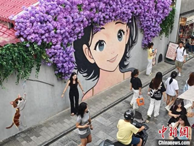 图为民众在西安老菜场文化创意街区的涂鸦墙前拍照。党田野 摄