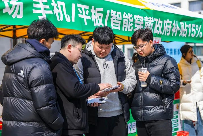 2025年3月6日，学生在山东省青岛恒星科技学院开展的消费品以旧换新活动中选购手机。（张鹰 摄）