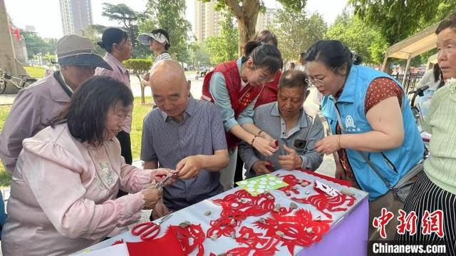 省级非物质文化遗产代表性传承人冯禄芝在剪纸区手把手教学。潞城区融媒体中心供图