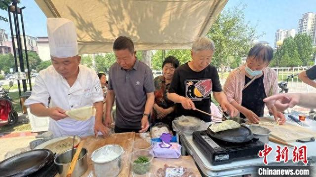 图为甩饼制作现场，居民们纷纷上手体验。潞城区融媒体中心供图