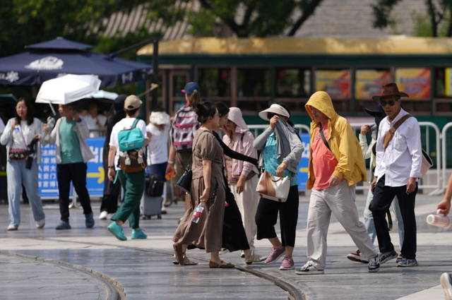 6月23日，在北京前门大街，游客穿着防晒服抵挡烈日。新华社记者 鞠焕宗 摄