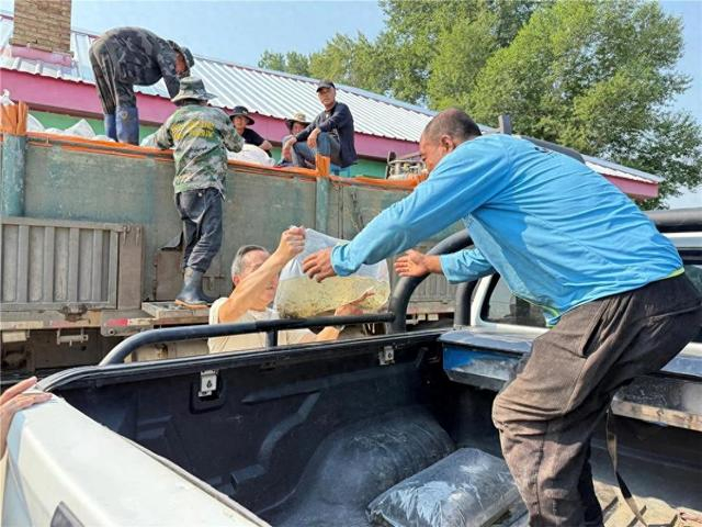 将充氧的鱼苗袋搬运至种植户车上。陶芊 摄