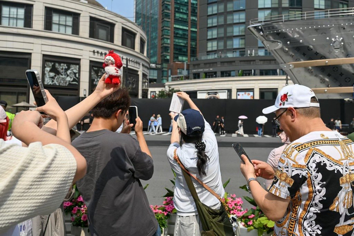 6月26日下午，上海石门一路吴江路附近，市民游客举着玩偶、日用品等拍照。澎湃新闻记者 朱伟辉 图