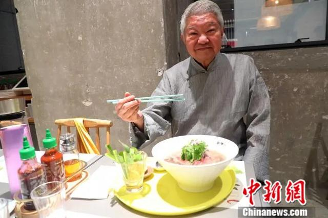 图为2018年7月3日，香港著名美食家蔡澜在香港品尝首家自制越南粉店的越南粉。中新社发 洪少葵 摄