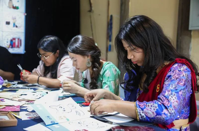 △ 在浙江省桐乡市濮院时尚古镇的一家拼布工作坊，外国游客在体验布艺创意拼贴。图片来源：新华社