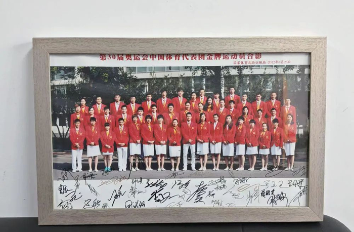 魏文斌办公室里摆放着第30届奥运会中国体育代表团金牌运动员合影，上面有运动员们的亲笔签名（鄂璠/摄）