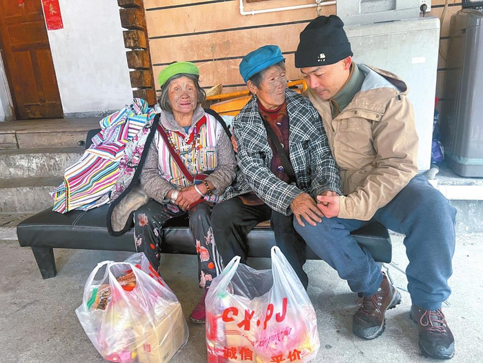 杨文彬（右一）看望独龙族文面女。图源：云南日报