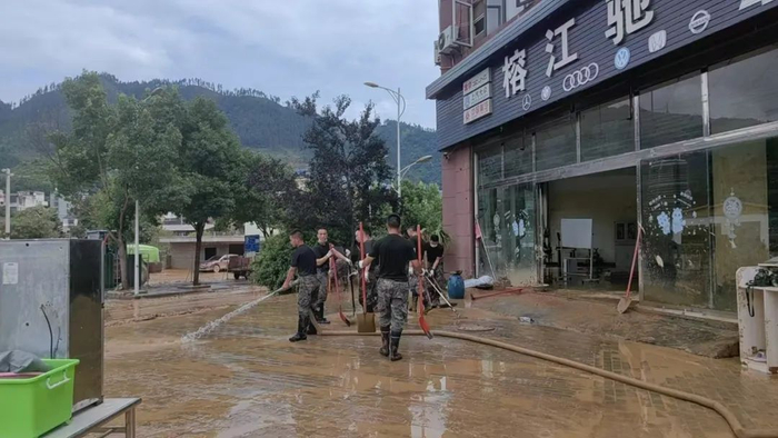 ▲6月29日早上，武警官兵在胡雨的店门口清淤。 受访者供图