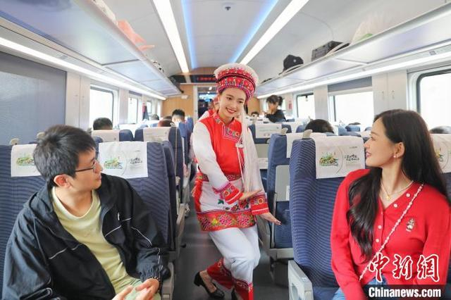身着民族服饰的列车乘务员与乘客互动。 陈畅 摄