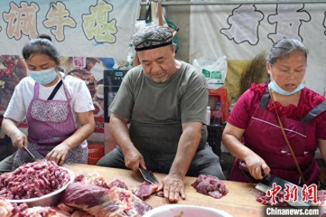 图为阿里木江在榕江参与到牛肉的切割工作中。张齐武摄