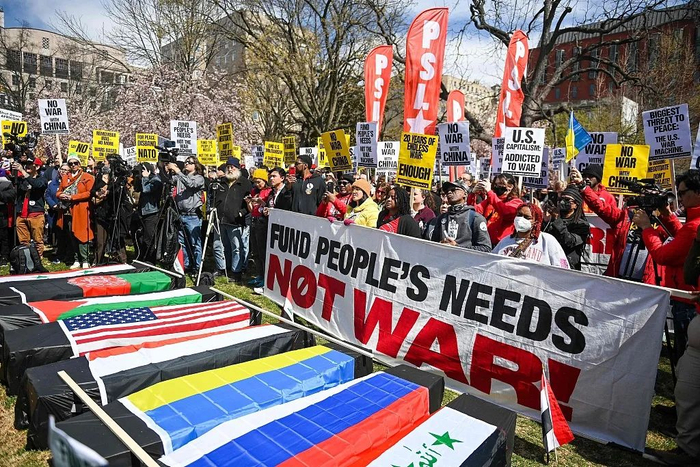 当地时间2023年3月18日，美国华盛顿特区，反战活动人士站在裹着美国国旗的棺材模型旁，在白宫前示威。