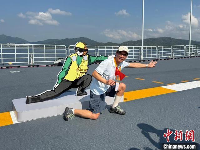 7月4日,山东舰举行开放参观活动。图为一位香港市民模仿航母舰载机起飞时起飞助理做出的姿势。中新社记者 戴梦岚 摄