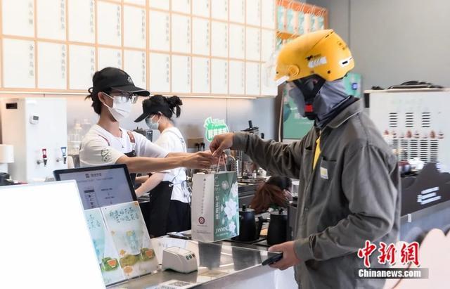 图为一名外卖员正取一份由茉莉花制成的奶茶。王伟臣 摄
