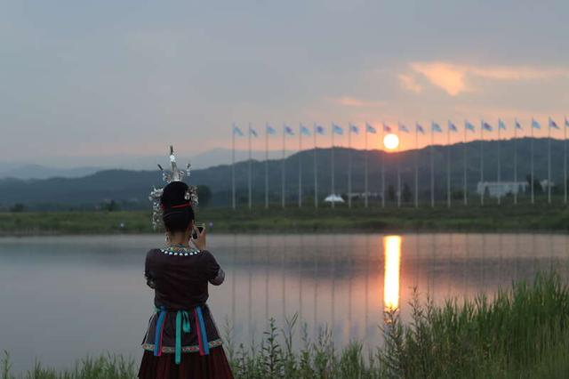 7月3日，内蒙古呼和浩特。一位身穿少数民族服饰的演职人员正在拍摄敕勒川上的夕阳。中青报·中青网记者 余冰玥/摄