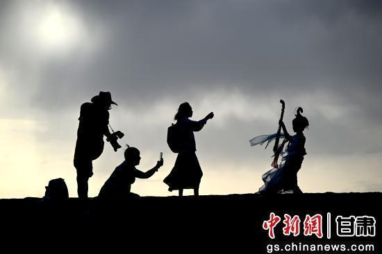 图为身着“飞天”服饰的游客在甘肃省敦煌市鸣沙山月牙泉景区拍照。张晓亮 摄