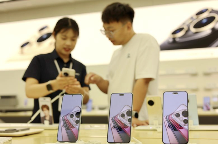 （7月9日，消费者在山东省滨州市一家手机专卖店选购手机。图片来源：新华社）