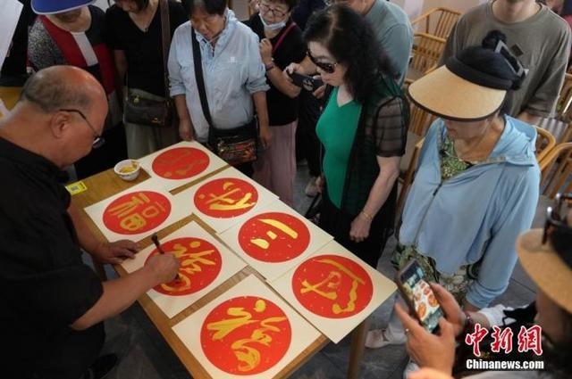 资料图:书法家为品尝过烙饼摊鸡蛋的居民撰写“过三伏”的福字。中新社记者 崔楠 摄