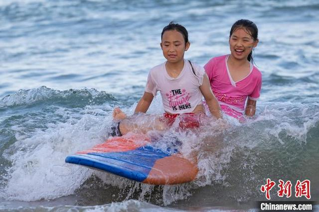图为小朋友坐在冲浪板上嬉水。中新社记者 骆云飞 摄 