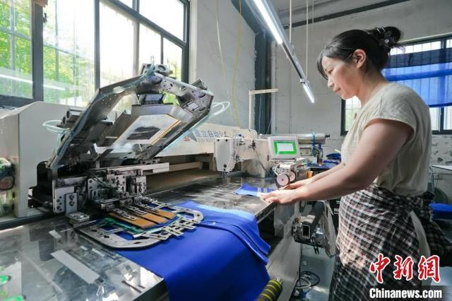 图为7月15日，河北弘润服饰有限公司的工人正在使用全自动贴袋机赶制来自海外的订单。 杜昕雨 摄 