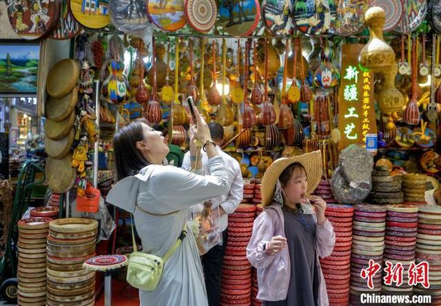 7月17日，新疆乌鲁木齐市大巴扎步行街，游客被琳琅满目的旅游商品所吸引。中新社记者 刘新 摄