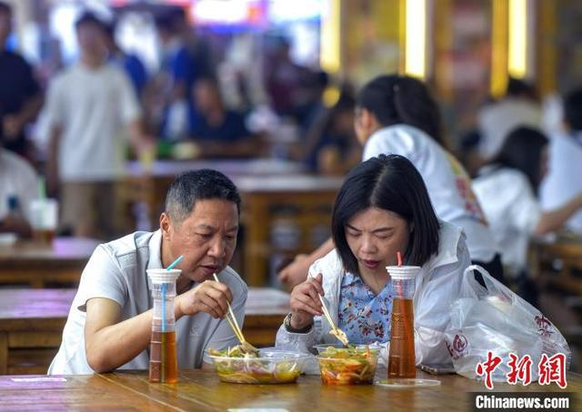 7月17日，新疆乌鲁木齐市大巴扎步行街，游客在美食街品尝新疆美食。中新社记者 刘新 摄