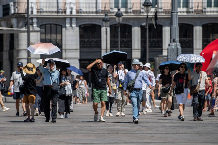 当地时间2025年7月17日，西班牙马德里，游客在太阳门进行徒步游并用阳伞遮阳。