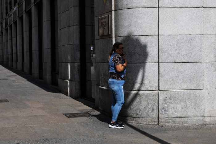 当地时间2025年6月20日，西班牙马德里，一名行人在高温下于阴凉处打电话。