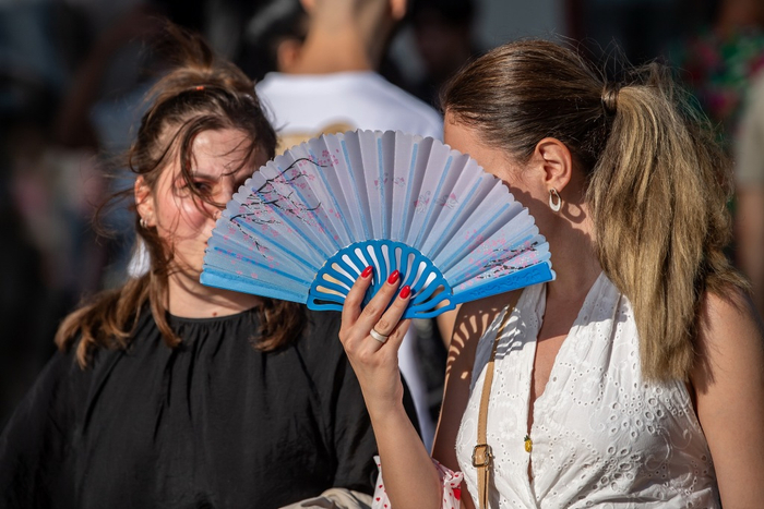 当地时间2025年7月16日，西班牙马德里，人们在大道上用扇子遮阳。