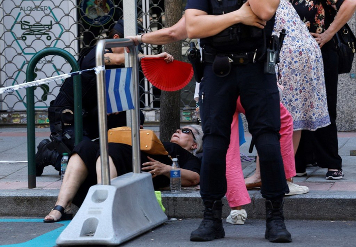 当地时间2025年7月5日，西班牙马德里，一名女子在街上因中暑晕倒，警察为她扇风降温。