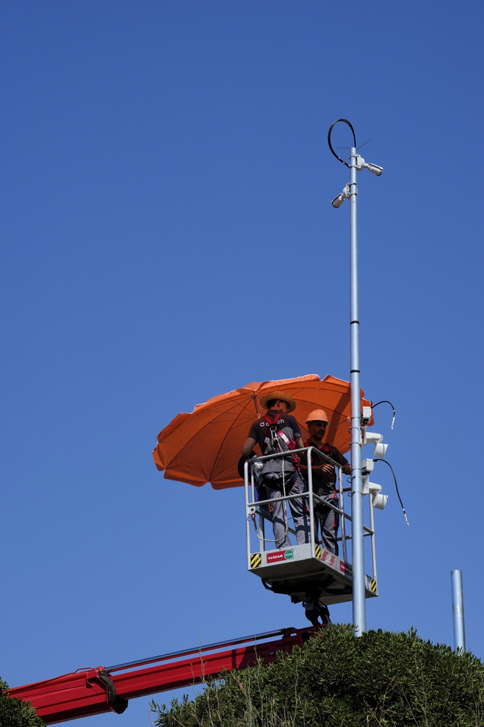 当地时间2025年6月30日，西班牙东北部巴塞罗那，工人在起重机上使用遮阳伞。