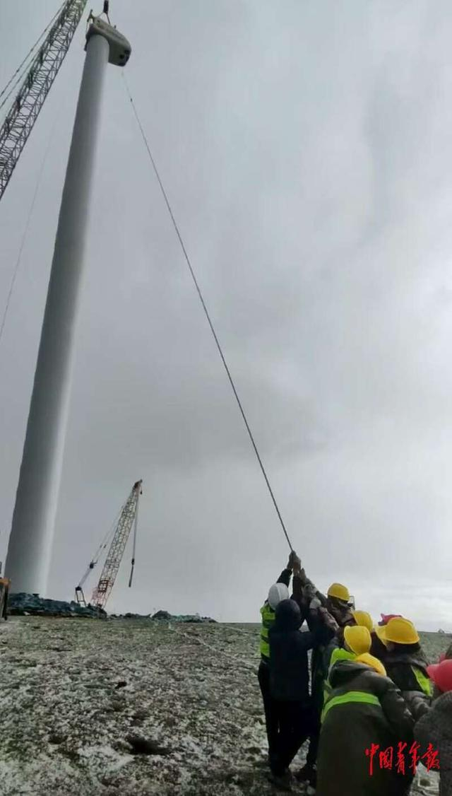 机舱吊装时突遇恶劣天气，现场管理人员与工人们共同拉紧缆风绳。受访者供图