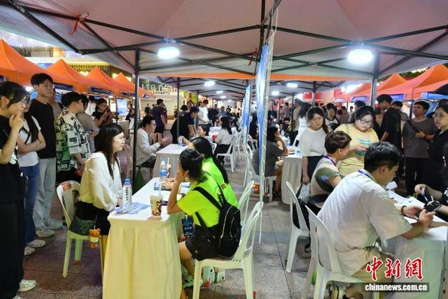 图为企业工作人员与求职者交谈。中新社记者 张斌 摄