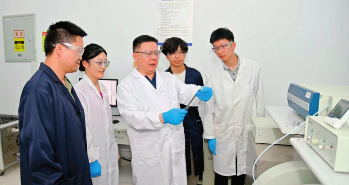 蒋军成（中）和团队成员在实验室交流讨论（2025 年 7 月 8 日摄） 受访者供图
