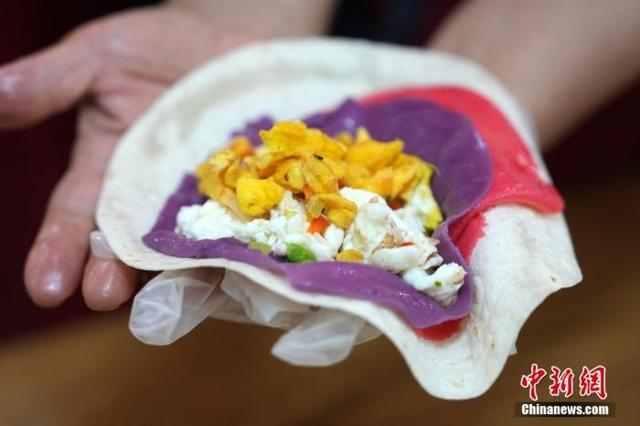 资料图：参与活动的居民手中的烙饼摊鸡蛋。中新社记者 崔楠 摄