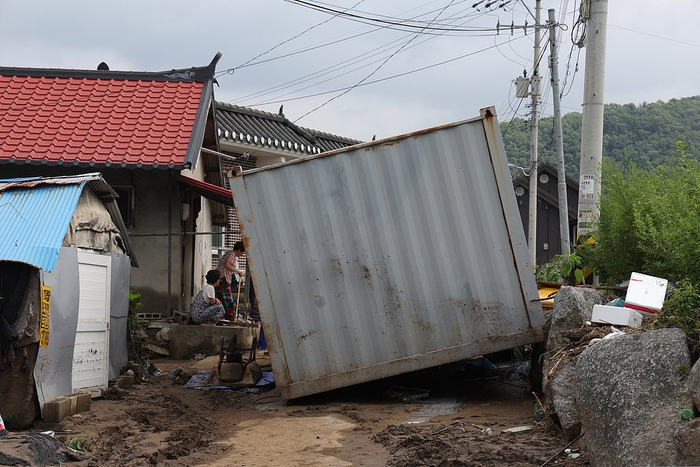 当地时间2025年7月21日，韩国京畿道加平郡大宝桥附近，一个集装箱倒在受洪灾影响的道路上。