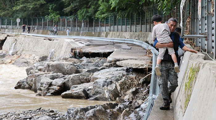 当地时间2025年7月20日，韩国京畿道加平郡，当地政府工作人员帮助因暴雨被困在当地住宿设施的游客撤离到安全区域。