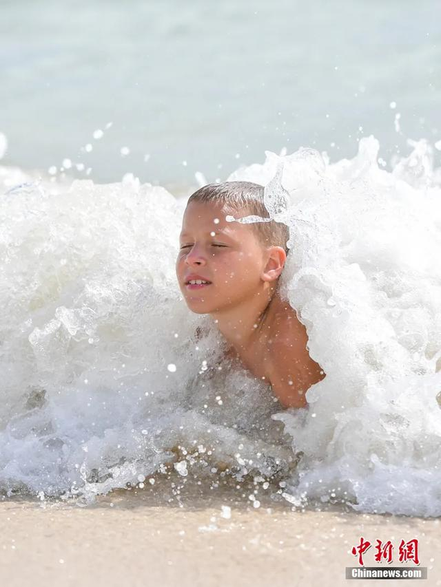 欢腾的浪花翻卷而来，清凉的海水漫过全身，这一刻，夏日海浴的惬意被定格。骆云飞 摄