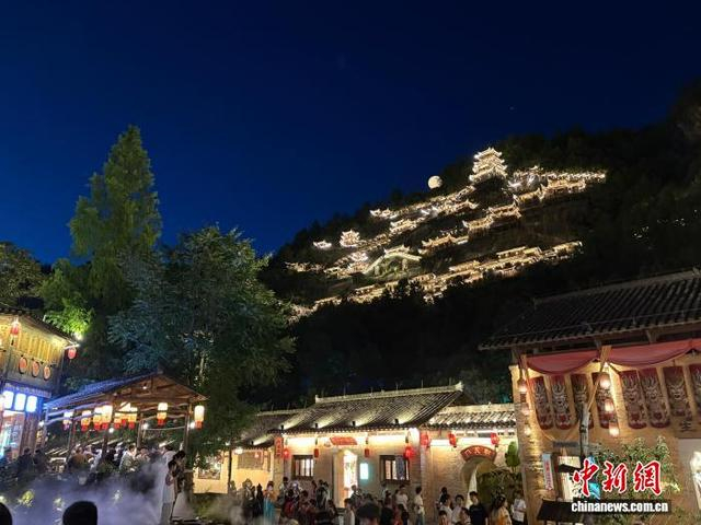 7月12日，在江西上饶望仙谷景区，“悬崖上的仙侠世界”吸引游客驻足观看。李韵涵 摄