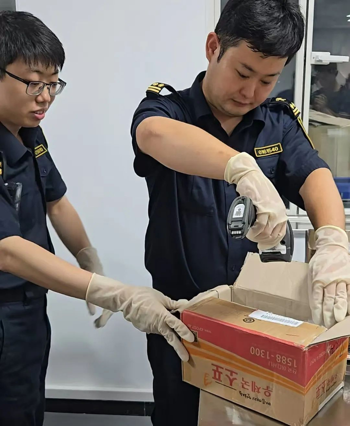 图为海关关员正在查验相关邮件。