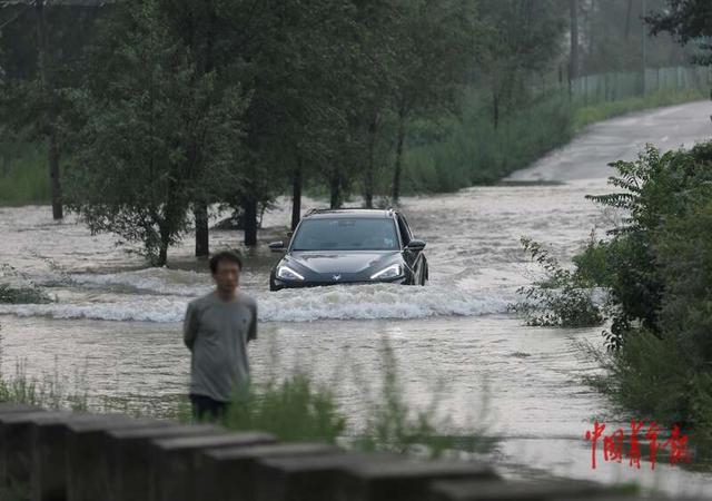 7月27日，北京密云水库碱厂大坝下游的碱万路，汽车趟水经过被洪水淹没的路段。中青报·中青网记者 陈剑/摄