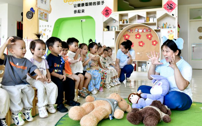 （7月22日，在山东省滨州市博兴县金色摇篮幼儿园，老师带托育班的孩子做游戏。图片来源：新华社）