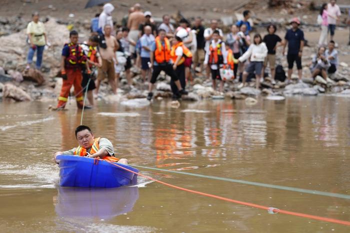 7月28日，北京市，怀柔区琉璃庙镇碾子湾村，消防员用固定好绳索的大塑料盆将被困游客运送到对岸。视觉中国 图