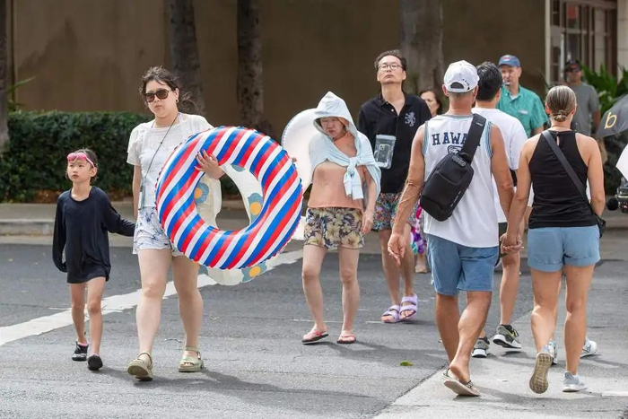 当地时间2025年7月29日，美国夏威夷瓦胡岛，人们在海滩上穿过街道。视觉中国 图
