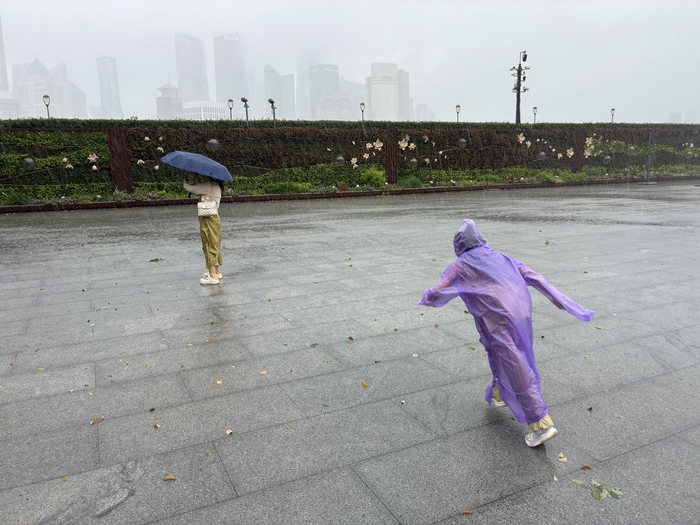 7月30日，风雨中，游客在外滩游玩。