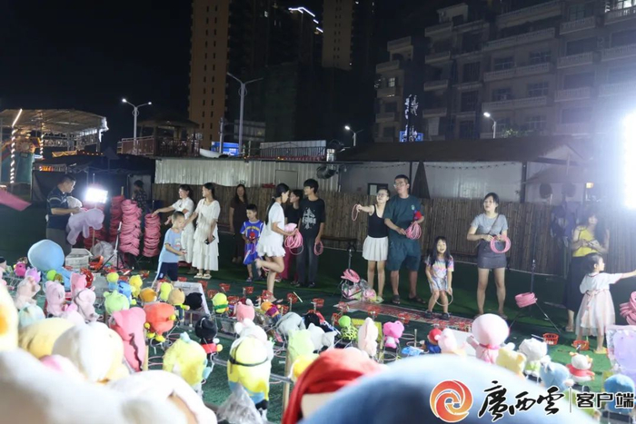 市民、游客在东兴市二桥夜市一家摊位抛圈套娃娃。
