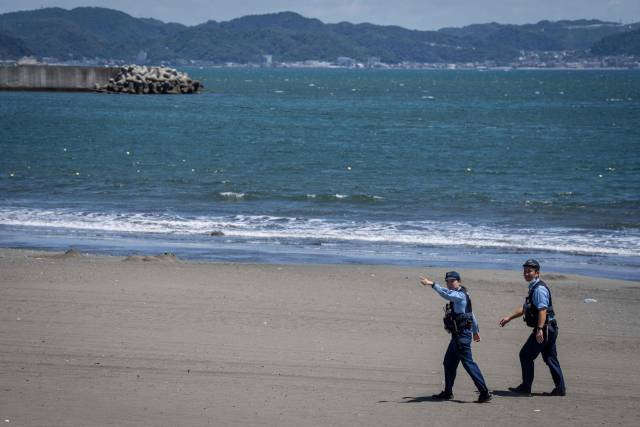 7月30日，在日本神奈川县藤泽市，警察要求人们从海滩撤离。图源新华社