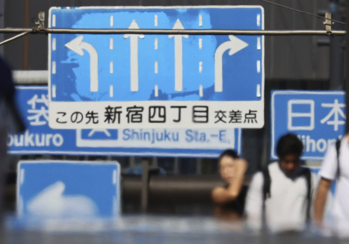 当地时间2025年7月29日，日本东京新宿区，热浪中的行人与指示牌。